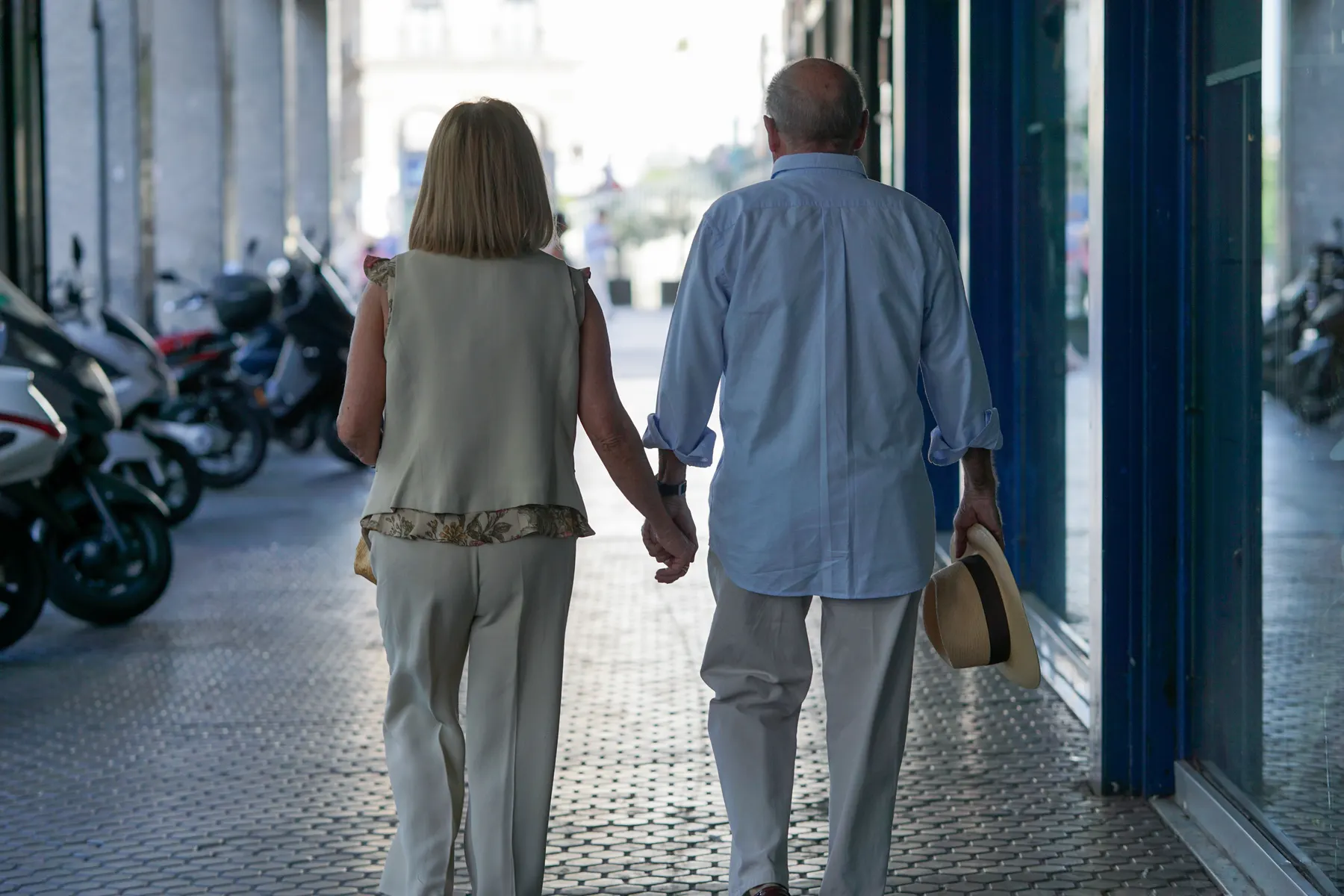 Couple walking hand in hand down a sunlit street
