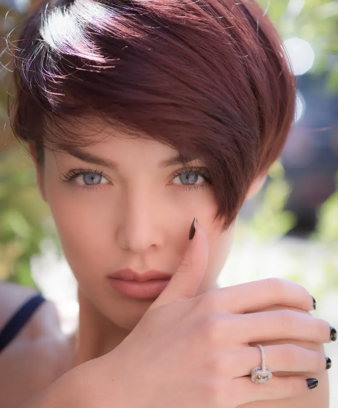 Close portrait of a woman with short hair, hand resting near her cheek