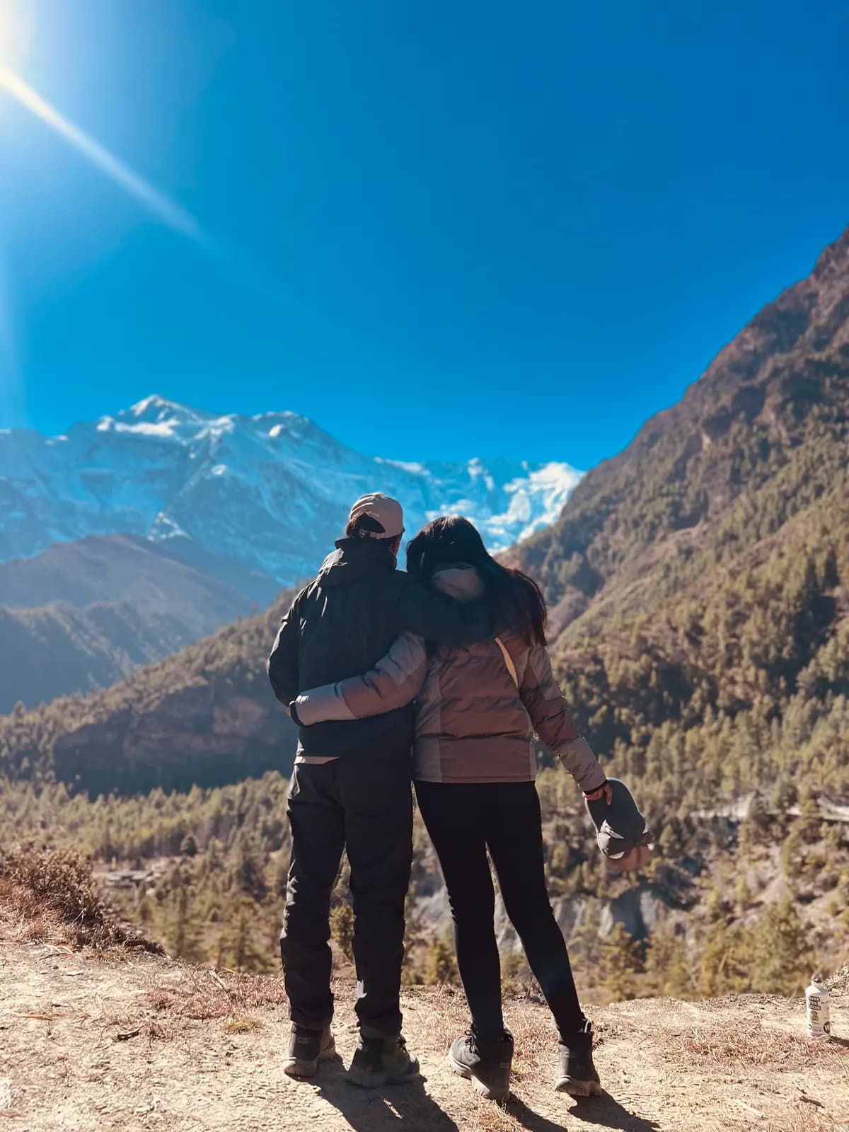 Couple holding each other on a mountain ridge during a session